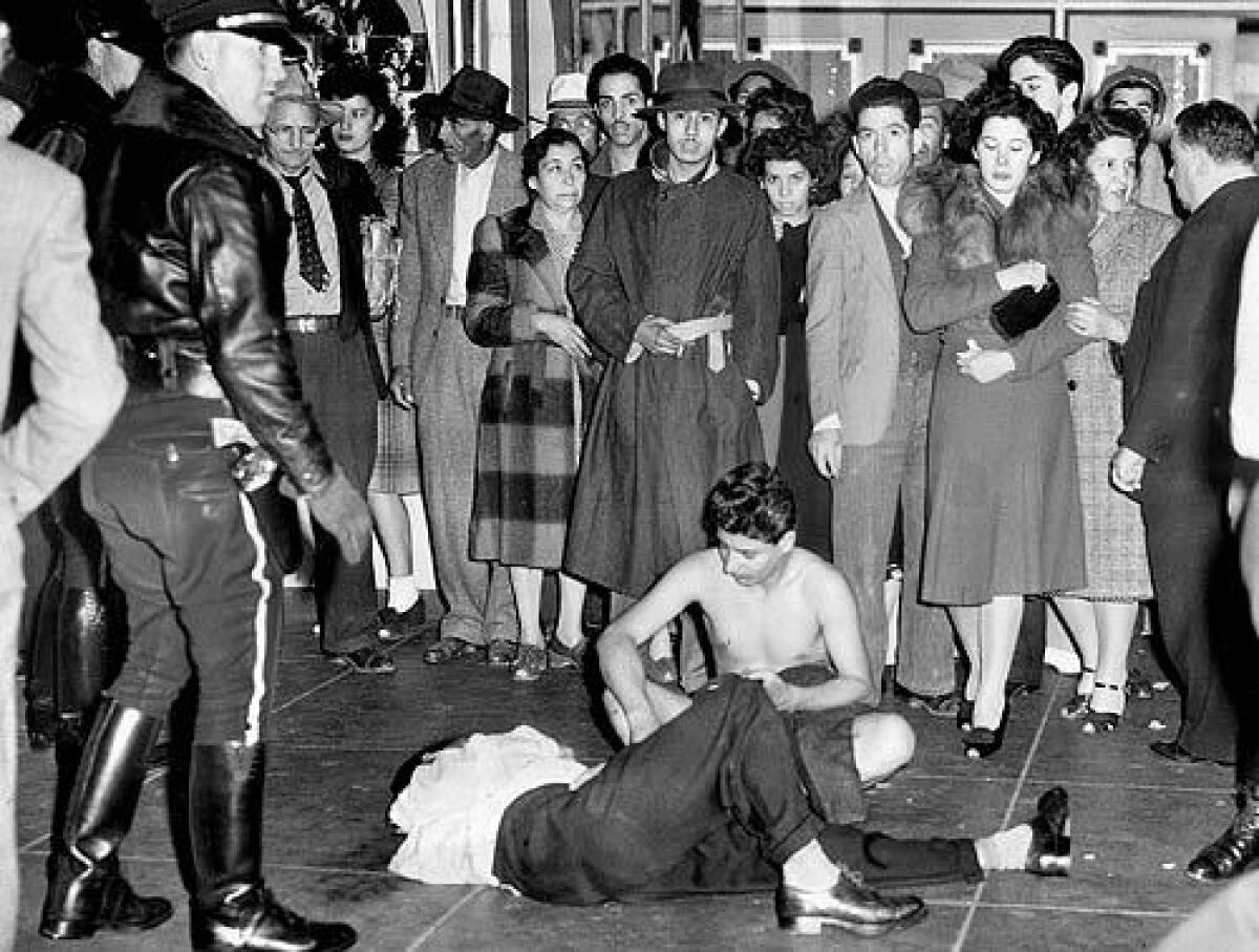 Two young men — one badly beaten, the other stripped of his clothes — draw a crowd during the Zoot Suit Riots in 1943.