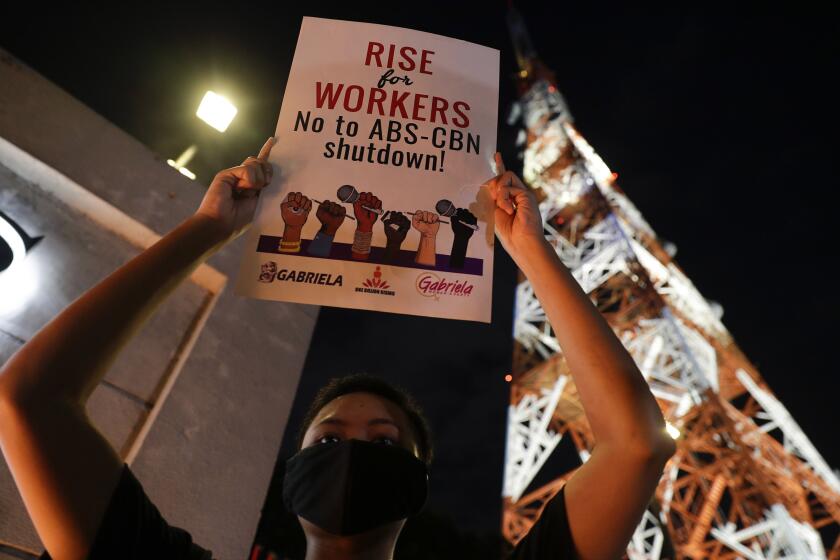 An activist holds a slogan outside the headquarters of broadcast network ABS-CBN corp. on Tuesday, May 5, 2020 in Quezon city, Metro Manila, Philippines. A Philippine government agency has ordered the country's leading broadcast network, which the president has targeted for it's critical news coverage, to halt operations after its congressional franchise expired, sparking shock over the loss of a major news provider during the coronavirus pandemic. (AP Photo/Aaron Favila)