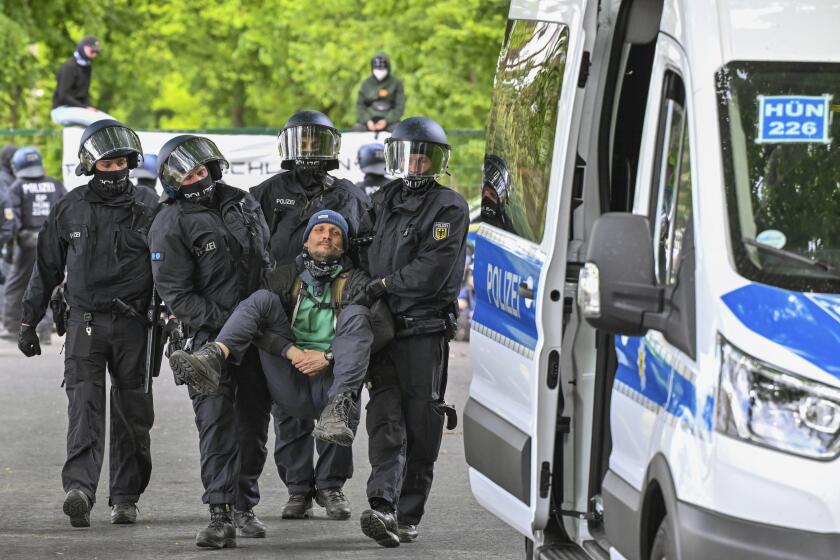 Police carry a activist from a blocade, at the access road to Neuhardenberg airfield, in Neuhardenberg, Germany, Friday, May 10, 2024. Tesla vehicles produced at the Gr'nheide plant are temporarily stored on the airfield site. (Patrick Pleul/dpa via AP)