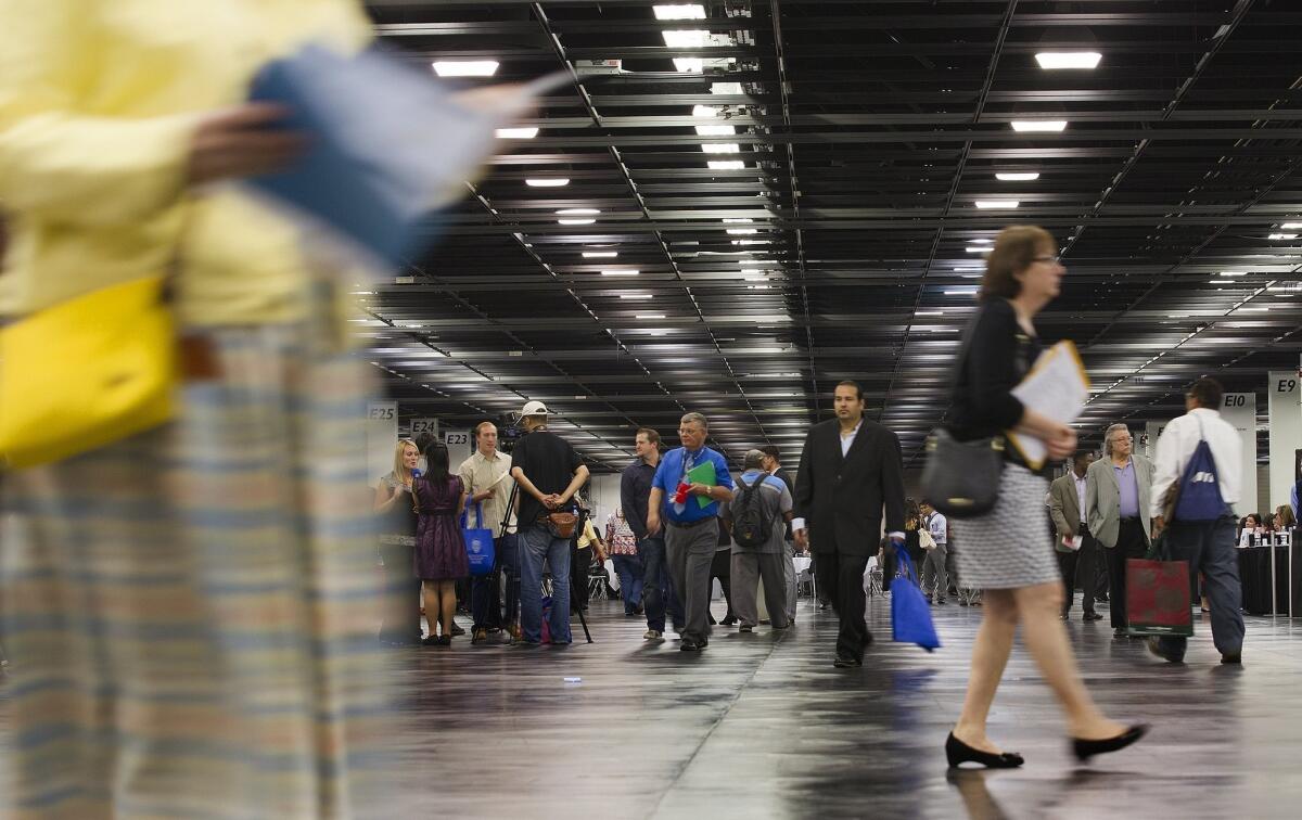 Workers in both the upper- and lower-income brackets have had their wages increase, while those in the middle have seen continued declines. Above, job seekers browse booths at a job fair in Anaheim last year.