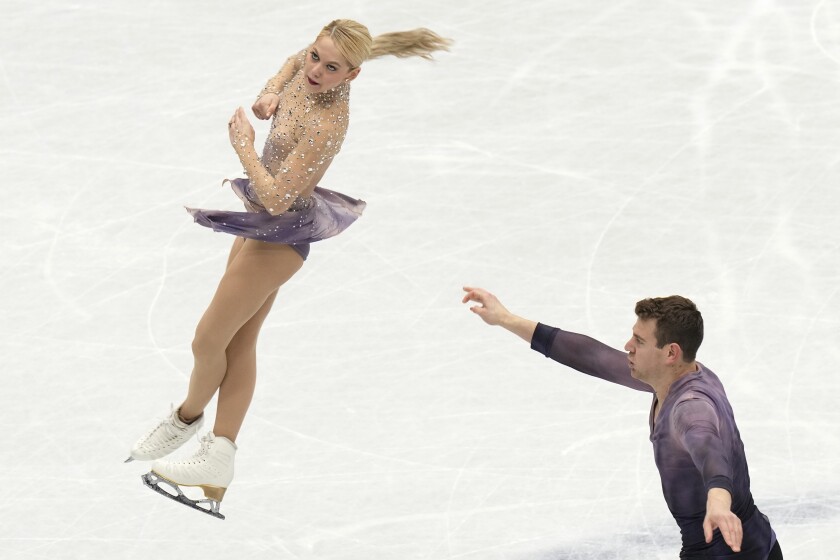 A female skater thrown by her male partner twirls in the air