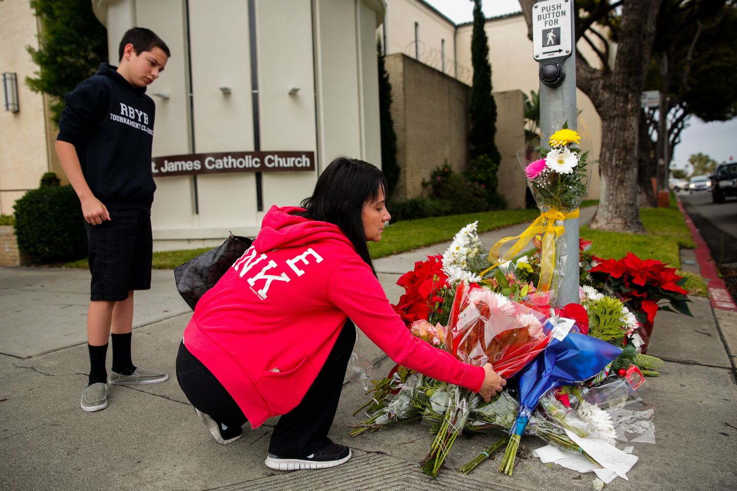 Jamie Rangel and her son Samuel Stromwall, 14, place flowers and say a prayer at the corner of Vincent Street and Pacific Coast Highway in Redondo Beach.