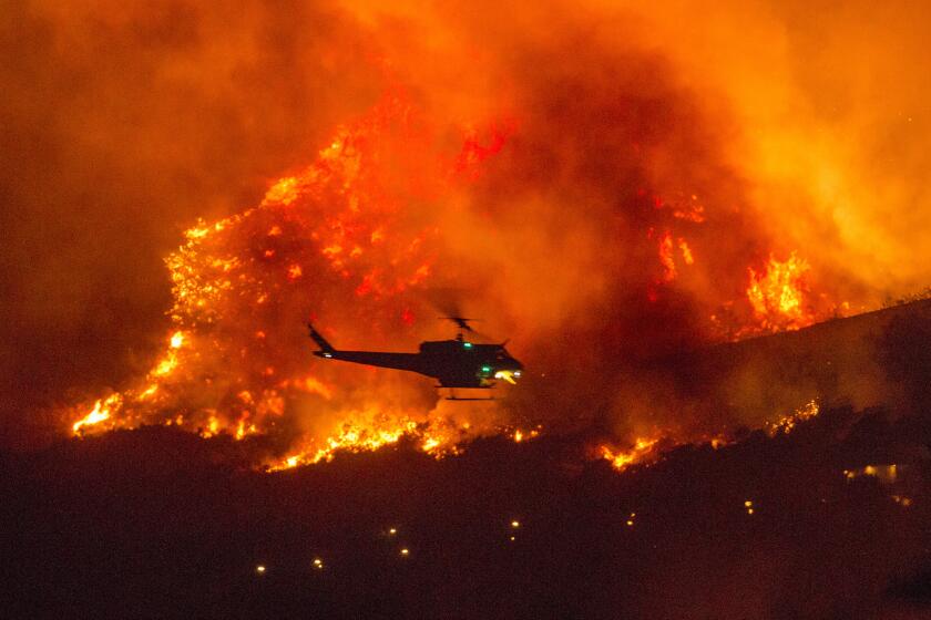 A helicopter prepares to drop water at a wildfire in Yucaipa, Calif., Saturday, Sept. 5, 2020. Three fast-spreading California wildfires sent people fleeing Saturday, with one trapping campers at a reservoir in the Sierra National Forest, as a brutal heat wave pushed temperatures into triple digits in many parts of state. (AP Photo/Ringo H.W. Chiu)