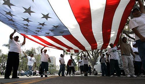 Marchers chant and carry a giant American flag down Ross Street in Santa Ana.