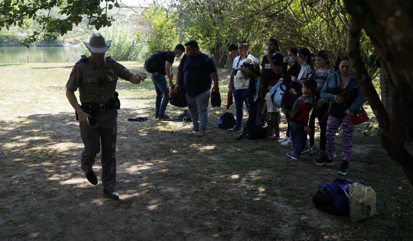 Texas Department of Public Safety officers work with a group of migrants who crossed the border.