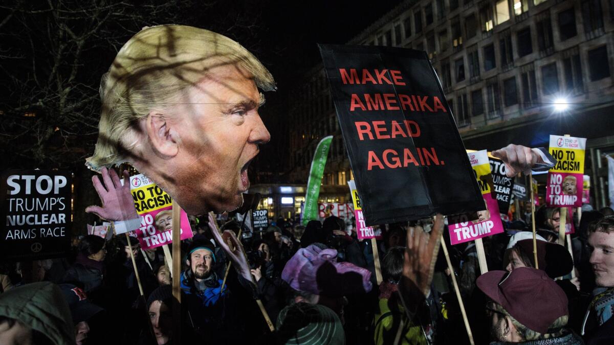 Protesters wave placards during a demonstration Friday against President Trump outside the U.S. Embassy in London.