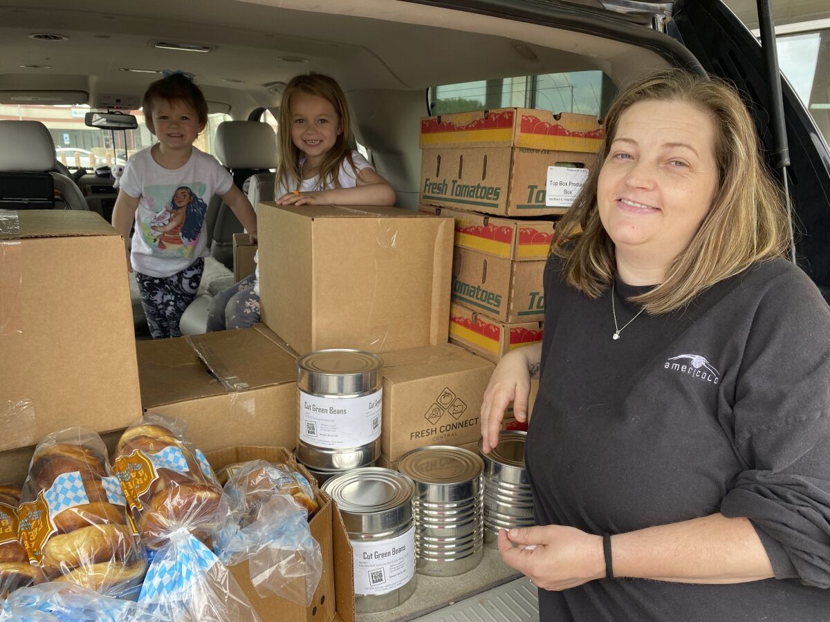 In this image provided by the Northern Illinois Food Bank, Kisha Galvan and her grandchildren, pose for a photo after stocking up on food items from the Northern Illinois Food Bank on May 26, 2022, in Rockford, Ill. Galvan was able to stock up on groceries for the week and buy extras like clothing and shoes at Walmart for her children last year. (Haley Overbeek/Northern Illinois Food Bank via AP)
