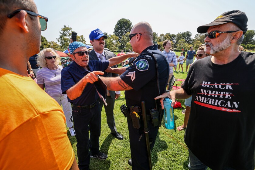 Police restrain vocal opponents of Representative Katie Porter (D-CA45) following a brief scuffle during a town hall meeting.