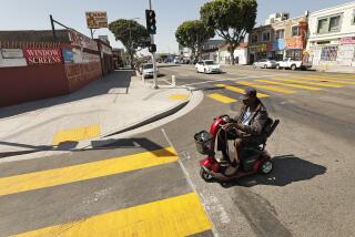 LOS ANGELES, CA - APRIL 17, 2019 - Ricky Kendrick, 66, uses new crosswalks at 43rd and Broadway which includes new sidewalks that extend further into the street, to slow vehicle speeds, and plastic bollards to stop cars from running up onto the sidewalk as L.A. struggles to reduce fatal traffic crashes on city streets. The city has added new infrastructure -- more visible crosswalks, flashing lights at crosswalks, digital signs that show drivers their speed -- to help protect pedestrians and bicyclists. (Al Seib / Los Angeles Times)