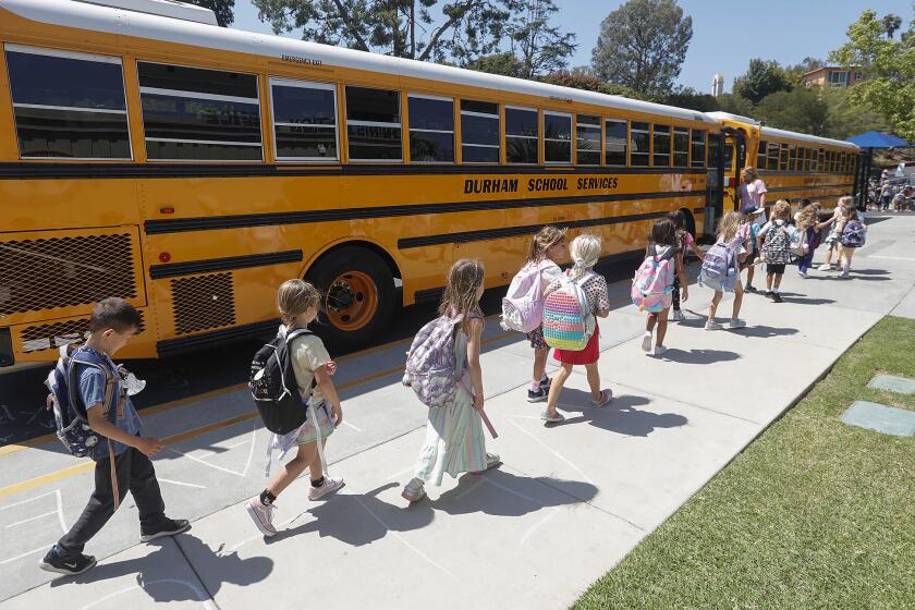 Kids follow their teacher as they walk single file to their home bus during first day of class at Top of the World elementary school in Laguna Beach in Monday.