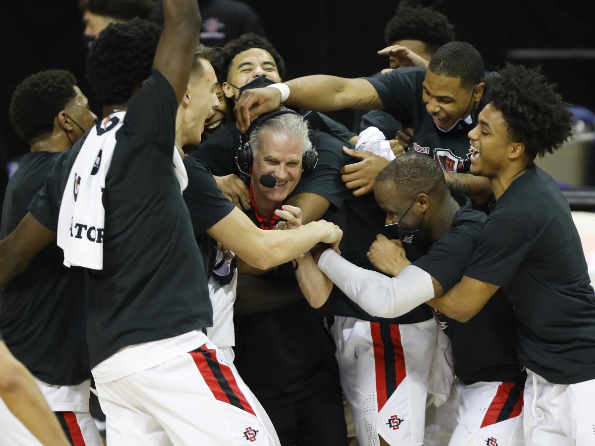 SDSU players surround coach Brian Dutcher after beating Utah State to win the Mountain West tournament.