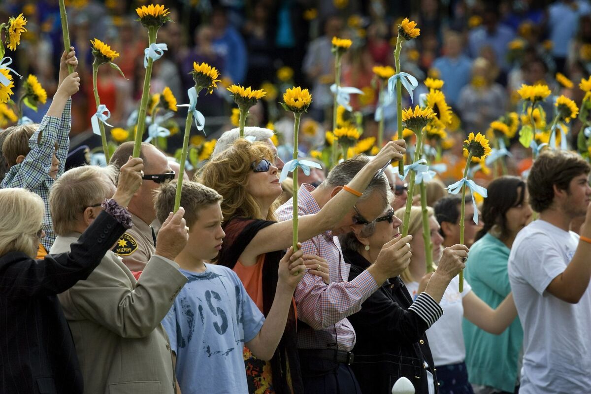 A crowd hold up sunflowers