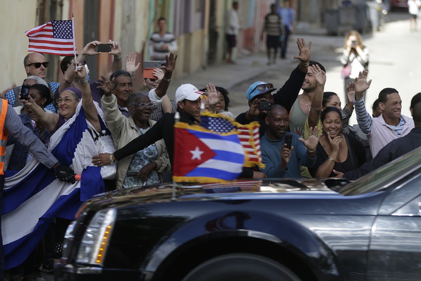 Cubans wave to President Obama as he passes through central Havana.
