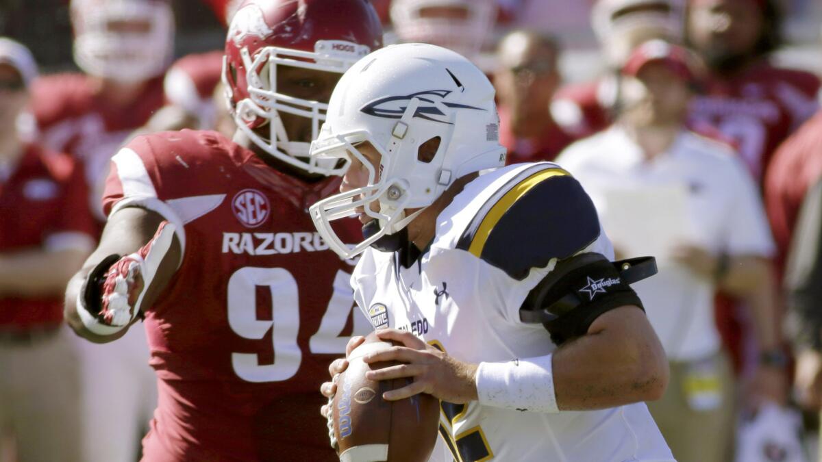 Toledo quarterback Phillip Ely, right, is pressured by Arkansas defensive lineman Taiwan Johnson (94) during the second quarter Saturday.