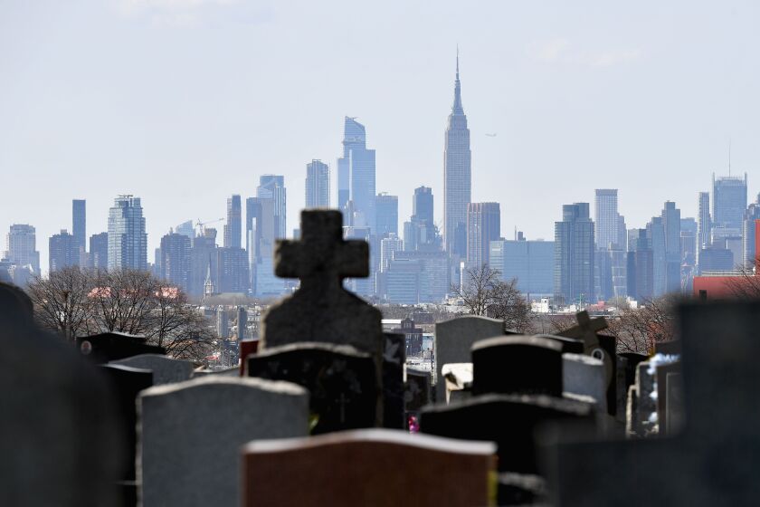 Gravestones from a cemetery are seen with the Manhattan skyline