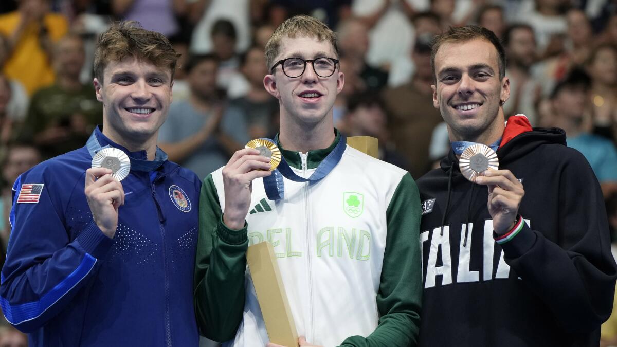 Irish gold medalist Daniel Wiffen stands on the with Americans Bobby Finke and Gregorio Paltrinieri