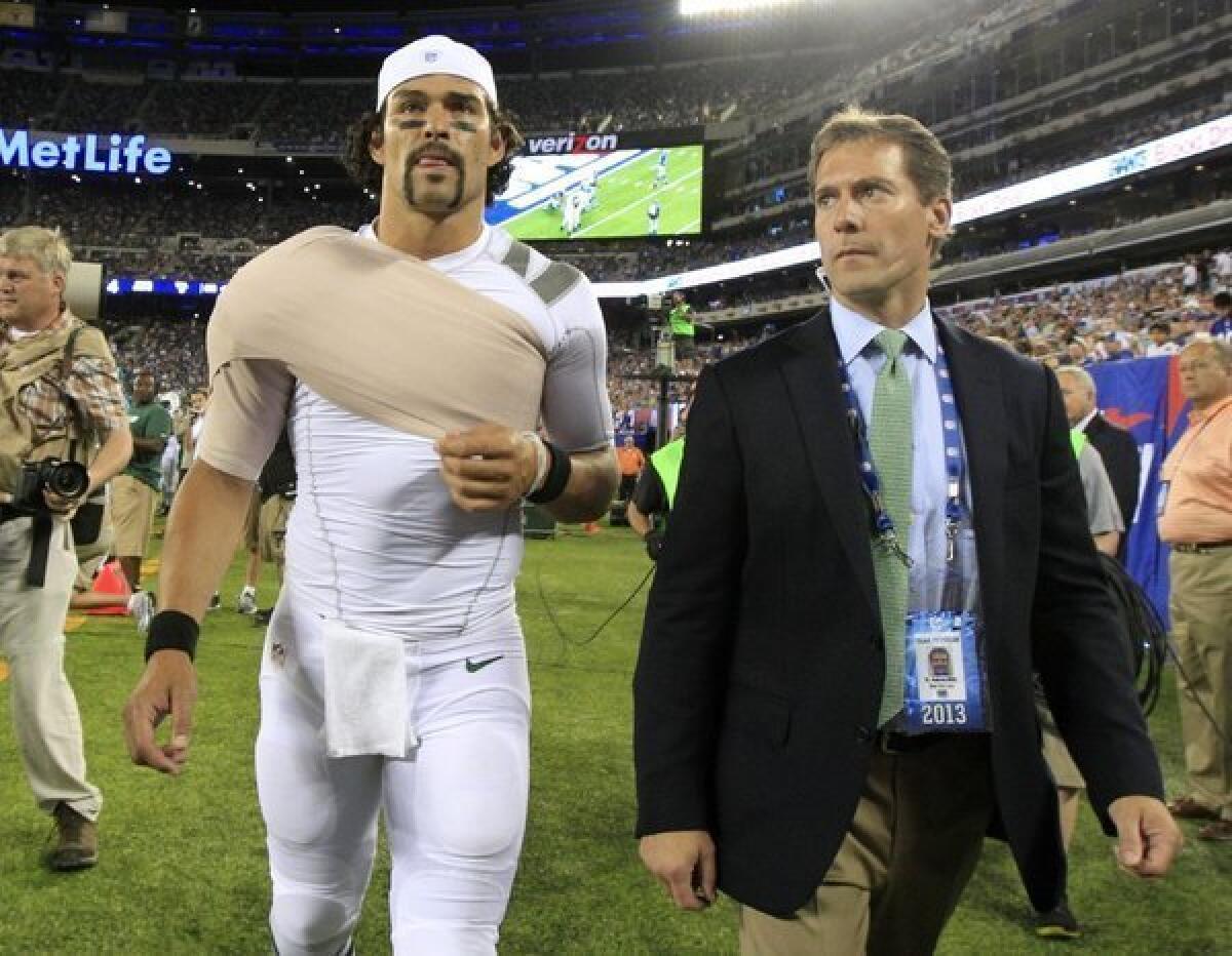 New York Jets quarterback Mark Sanchez walks off the field with Dr. Andrew Willis in August.