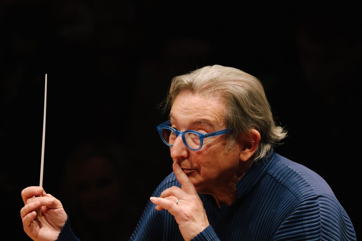 Michael Tilson Thomas, in a blue T-shirt, presses his finger to his lips as Los Angeles Phil leads 