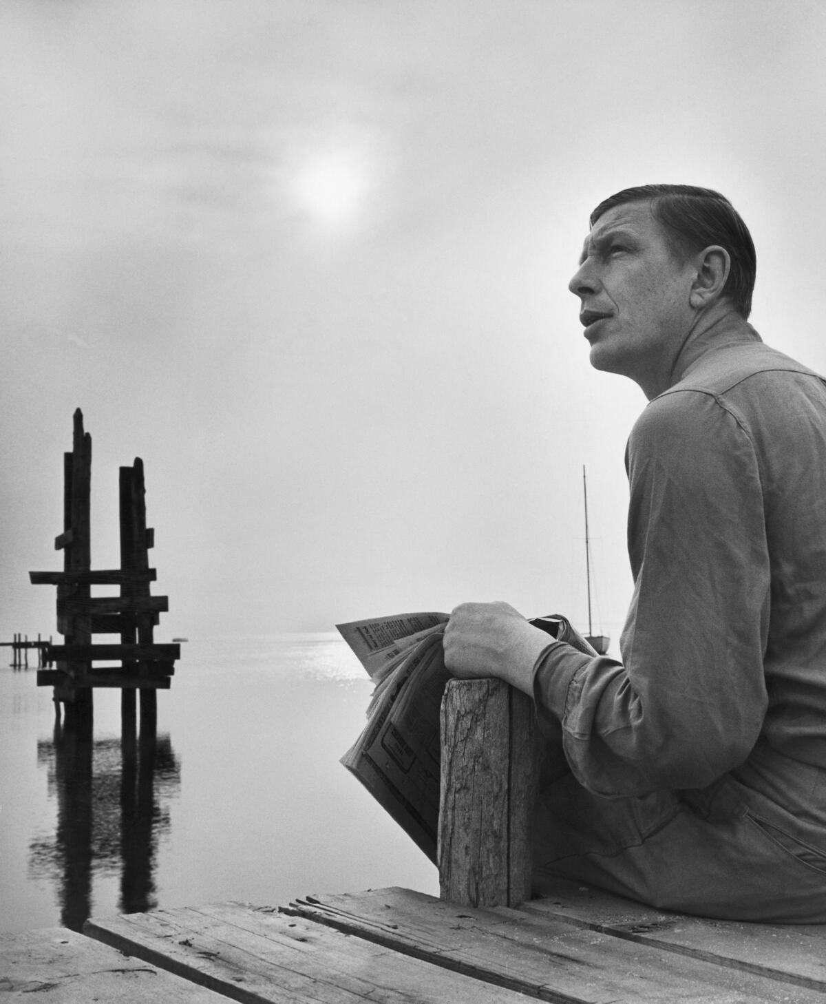 Poet W.H. Auden reads a newspaper on Fire Island, New York.