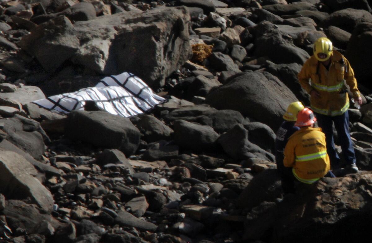 Rescue personnel watch over a body found at the foot of a 150-foot cliff at Point Fermin in San Pedro.