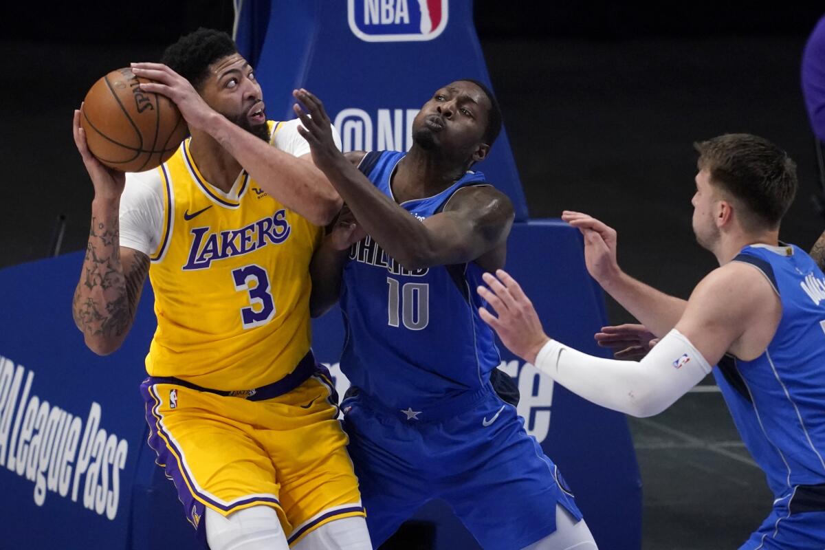Lakers' Anthony Davis works against Dallas Mavericks' Dorian Finney-Smith and Luka Doncic for a shot.