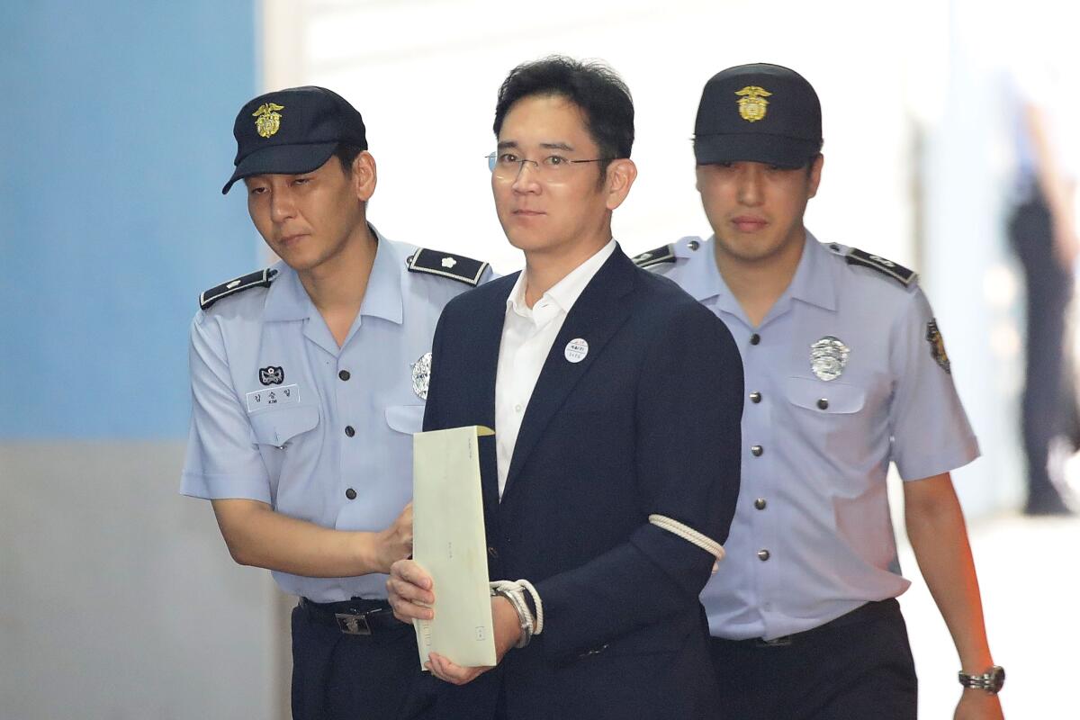 Samsung heir Lee Jae-yong escorted by two police officers