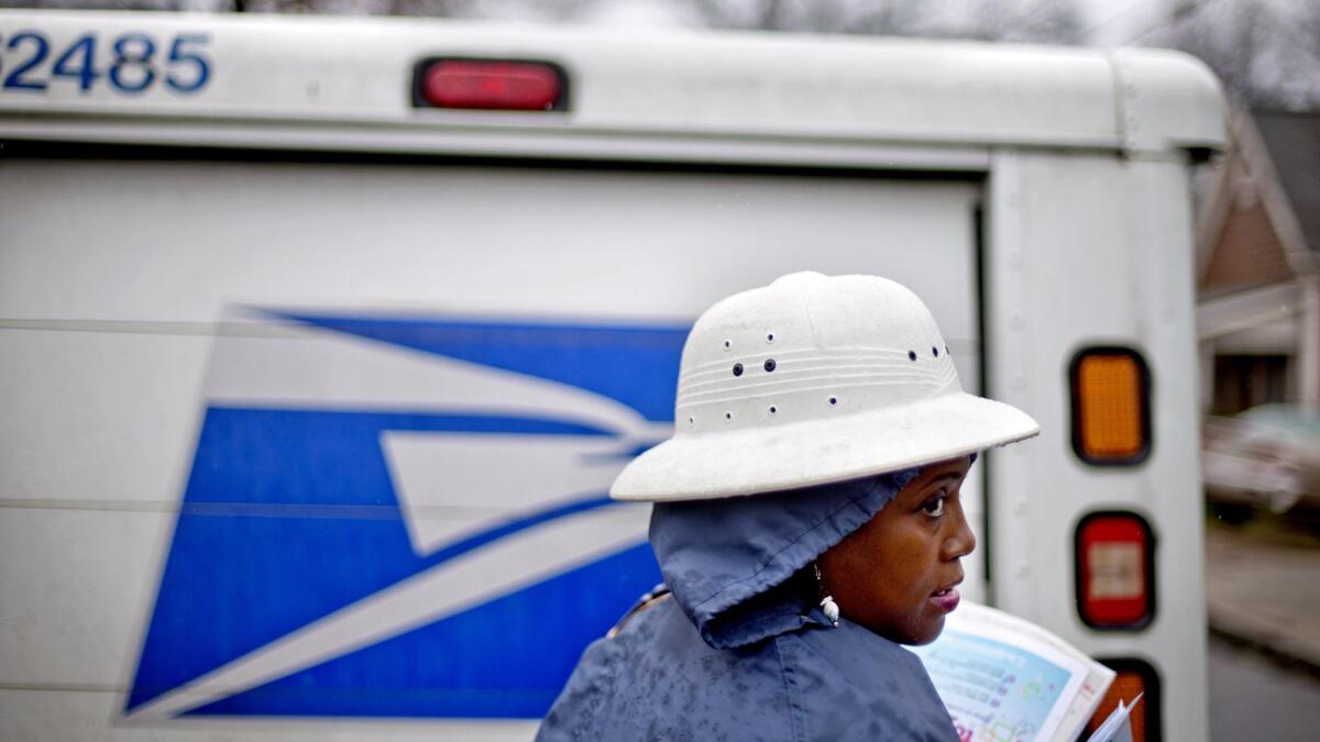 U.S. Postal Service letter carrier Jamesa Euler delivers mail in the rain in Atlanta. The Postal Service says it makes money on a deal signed with Amazon in 2013.