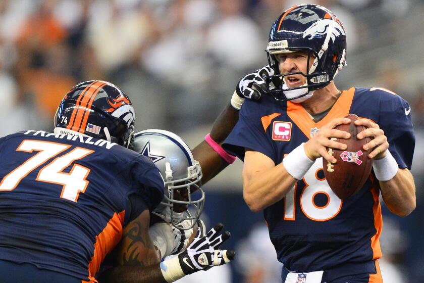 Broncos quarterback Peyton Manning tries to escape the grasp of Cowboys defensive end George Selvie in the first half Sunday.