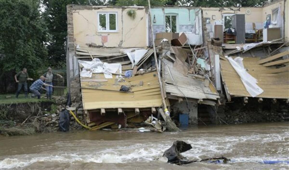 Residents try to get a bag out of roof of a destroyed house after a flash floods hit the town of Bogatynia, Poland, Sunday, Aug. 8, 2010. The flooding has struck an area near the borders of Poland, Germany and the Czech Republic. (AP Photo/Petr David Josek)