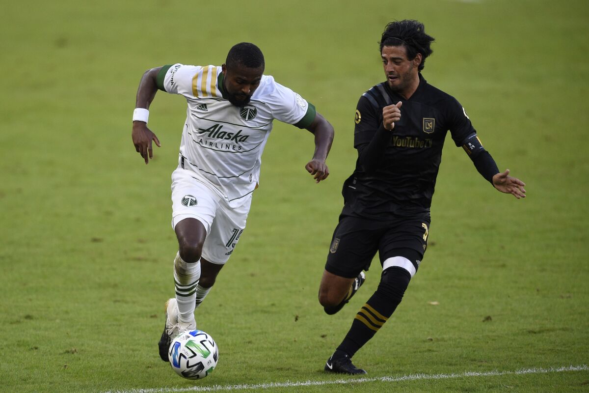 Portland Timbers defender Chris Duvall, left, moves the ball while pressured by LAFC forward Carlos Vela.
