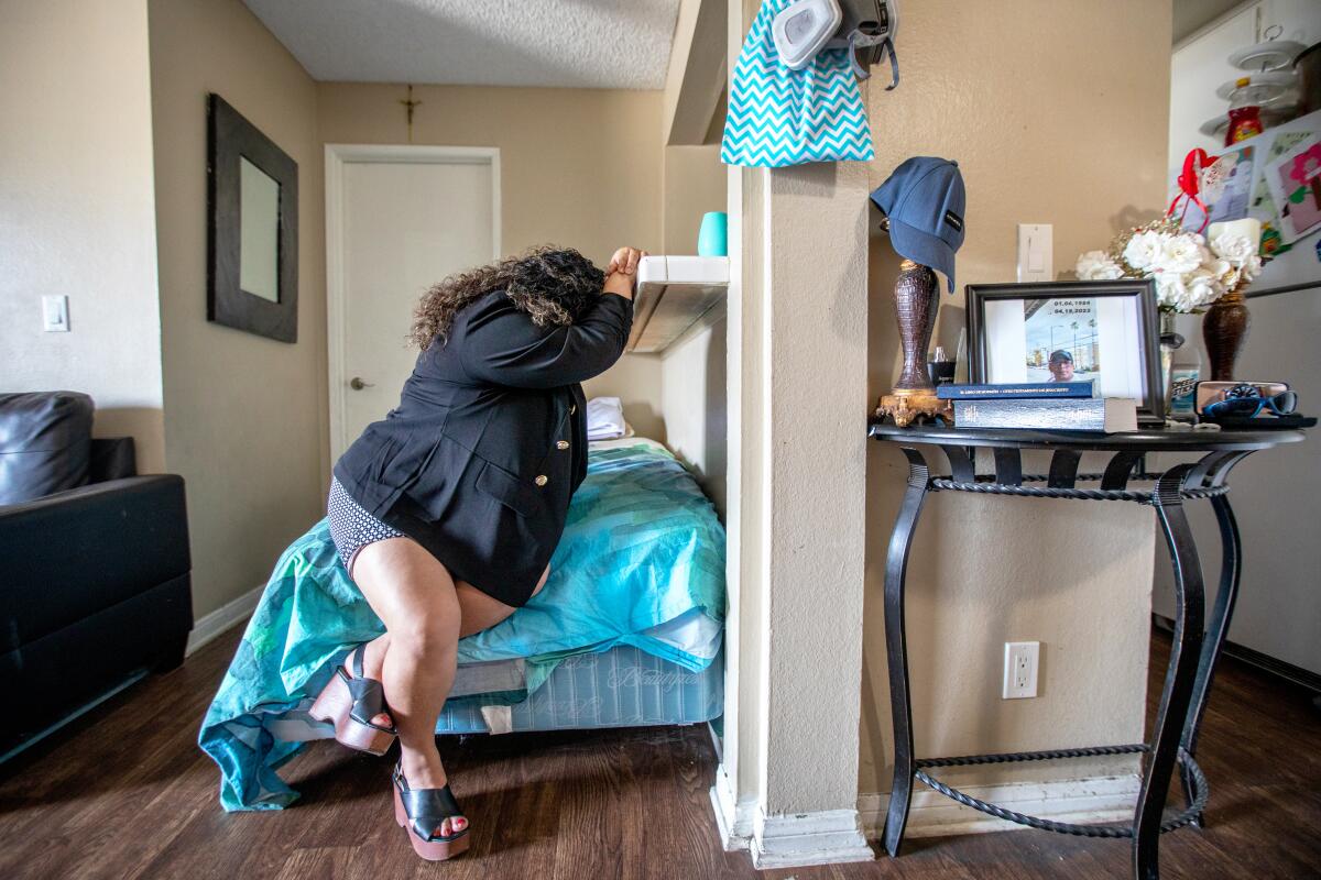 Ruth López sits on the edge of her bed, resting her head in her arms