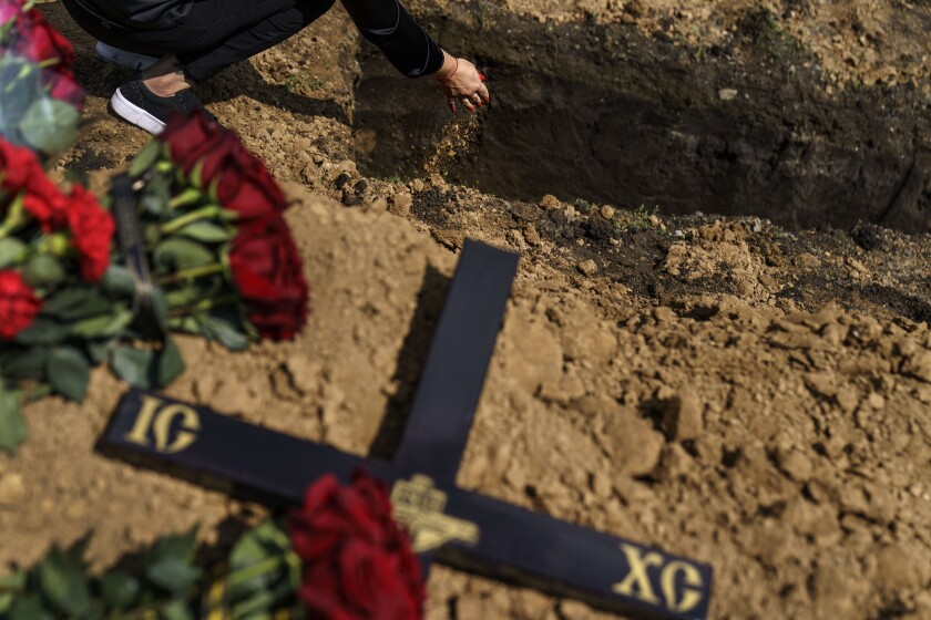 A woman drops a handful of dirt on the casket of her father during his burial service in Pokrovsk, eastern Ukraine.