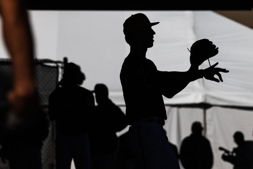 Alek Jacob, center, is silhouetted as he pitches during the first day of Padres spring training workouts.