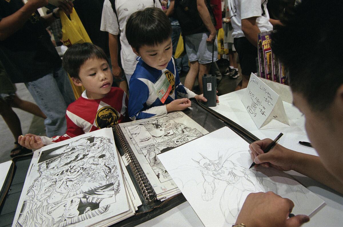 Billy Cheng, 5, left, and his brother, Sunny, 6, of San Francisco watch as Ron Lim of Marvel Comics sketches Batman in 1996.