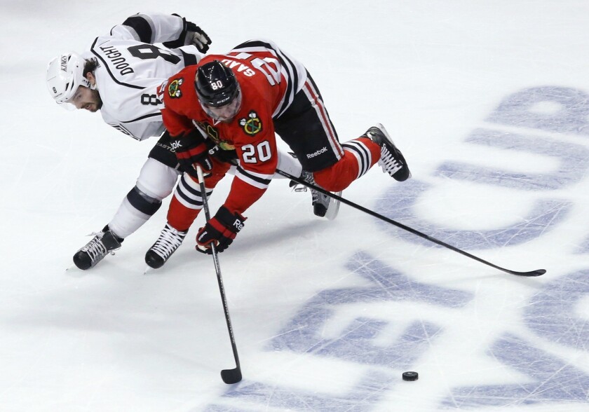 Kings defenseman Drew Doughty reaches around Blackhawks left wing Brandon Saad in an attempt to poke the puck away during the first period of Game 5 on Saturday evening at the United Center in Chicago.