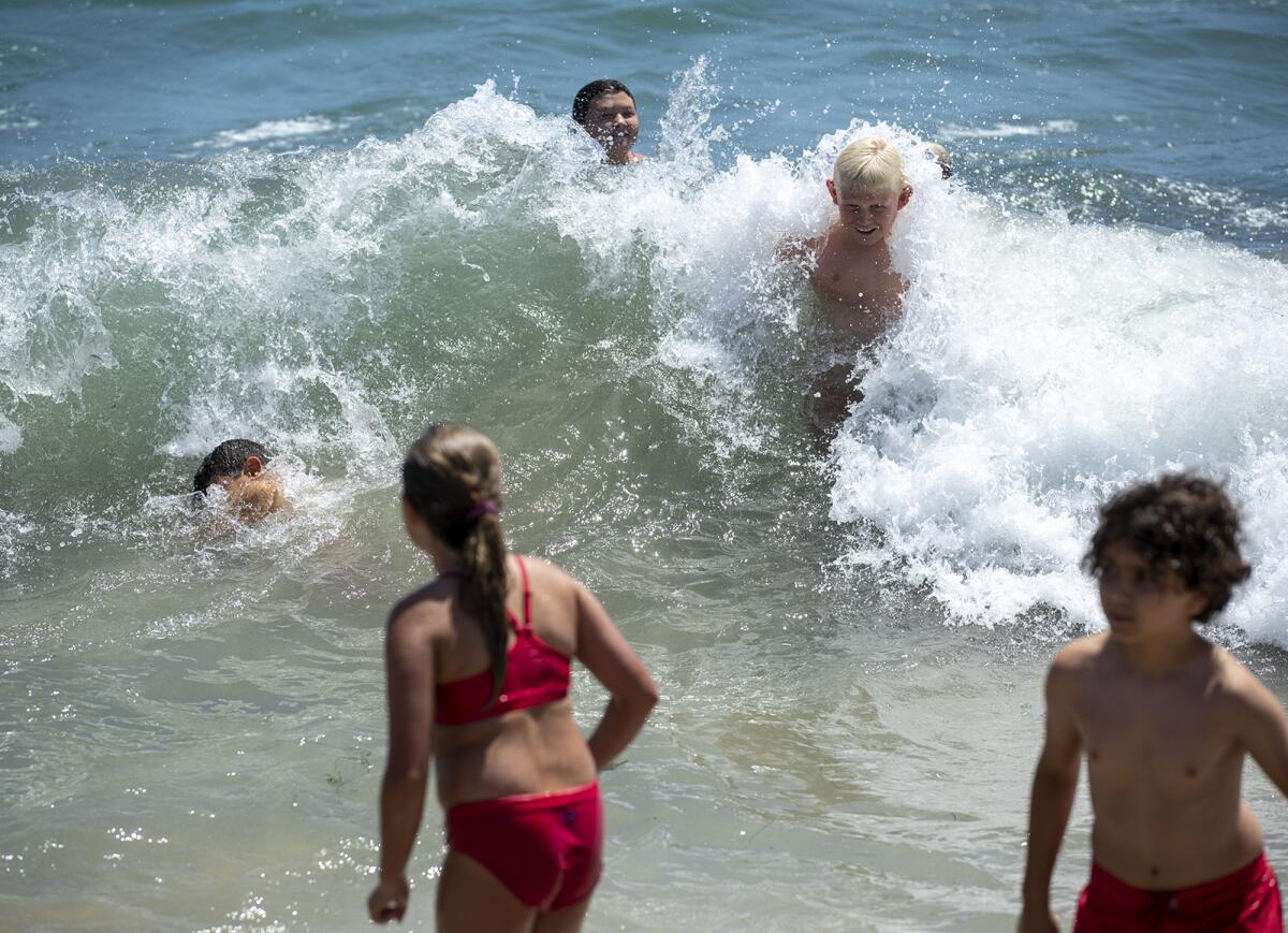 A group of Newport Beach Junior Lifeguards jump into a wave.