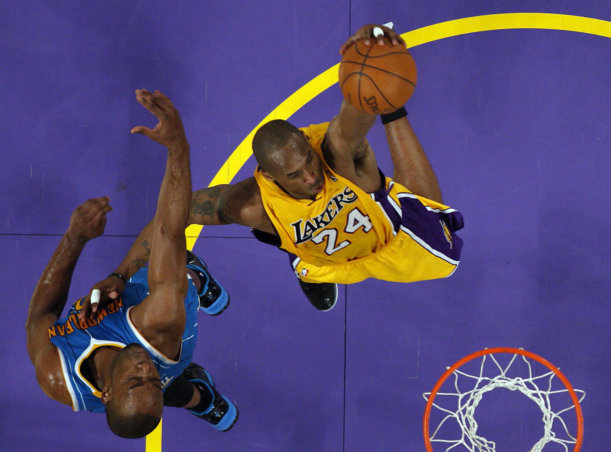 Kobe Bryant elevates past Hornets defender Carl Landry for a slam dunk.