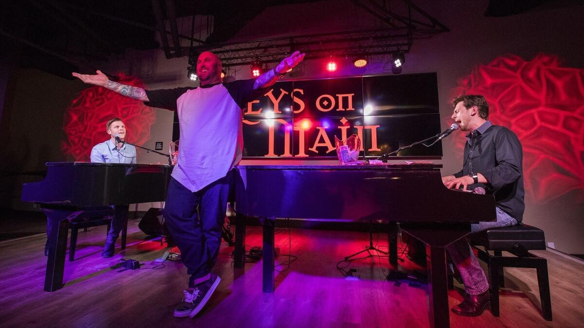 Aaron Buckner, left, and George Hasenohrl sing to Russell Long, center, during the March 9 grand opening of Keys on Main, a dueling piano bar at the Triangle in Costa Mesa.