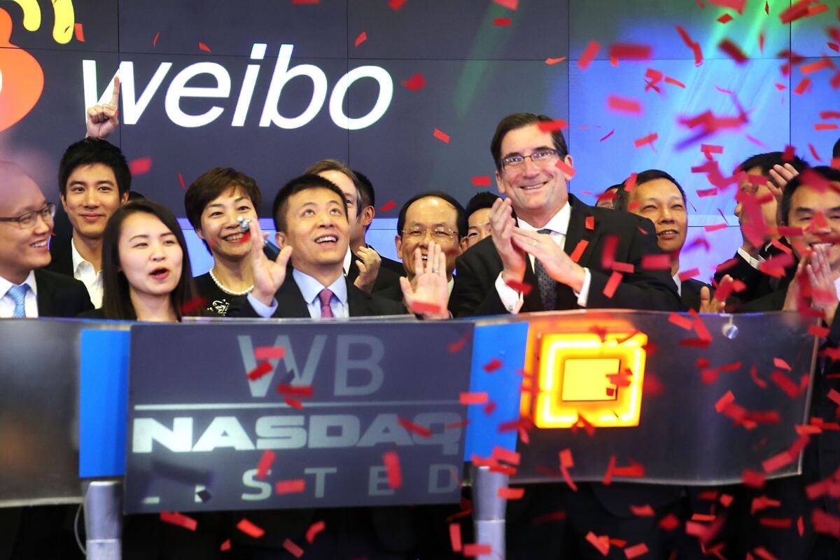 Charles Chao, center, chief executive of Weibo parent company Sina Corp., stands with Robert Greifeld, Nasdaq CEO, moments after Weibo began trading on the Nasdaq exchange.