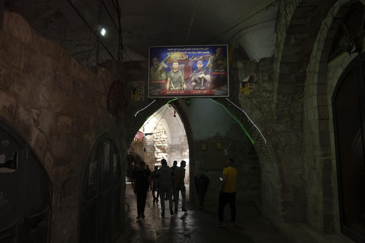 People walking under arches and a banner depicting Palestinian militants