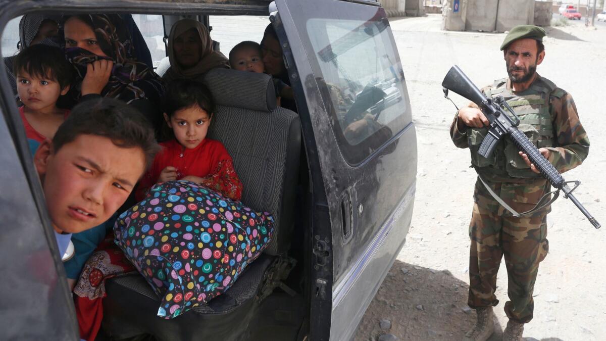 An Afghan security officer checks a family who fled the volatile city of Ghazni on Monday.