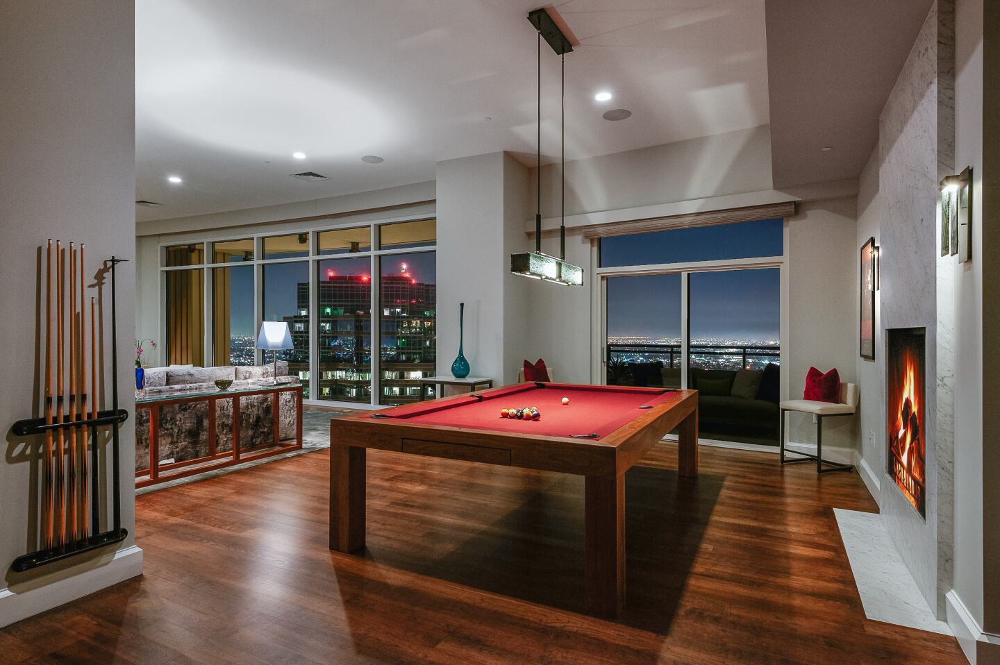 A pool table sits in an airy room with wood floors and large windows.
