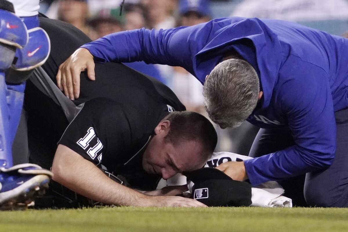 Home plate umpire Nate Tomlinson is helped by a Dodgers trainer after he was hit in the face by a broken bat.