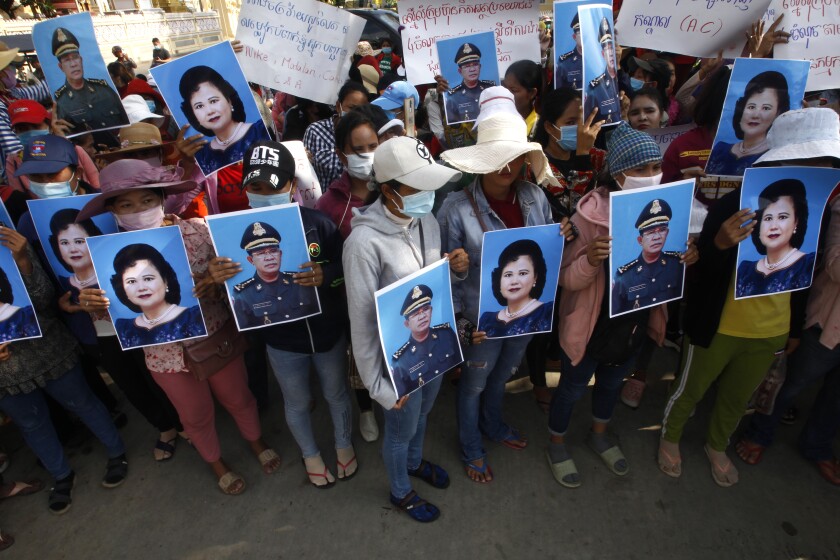 Garment workers, holding portraits of the prime minister and his wife, protest for benefits after their factory closed.