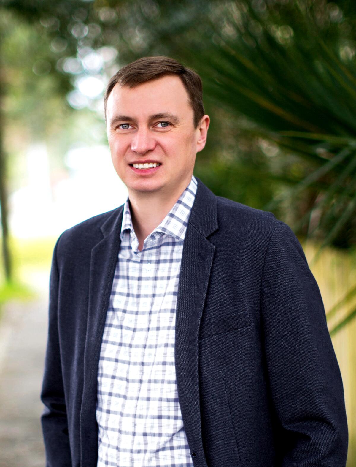 A portrait of a man wearing a collared shirt and blazer.