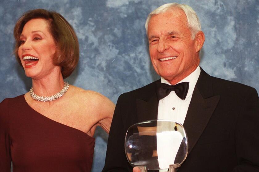In this Saturday, Nov. 1, 1997, file photo, Television executive Grant Tinker holds up his Hall of Fame award alongside his ex-wife Mary Tyler Moore at the Academy of Television Arts & Sciences' 13th Annual Hall of Fame induction ceremonies in Los Angeles.