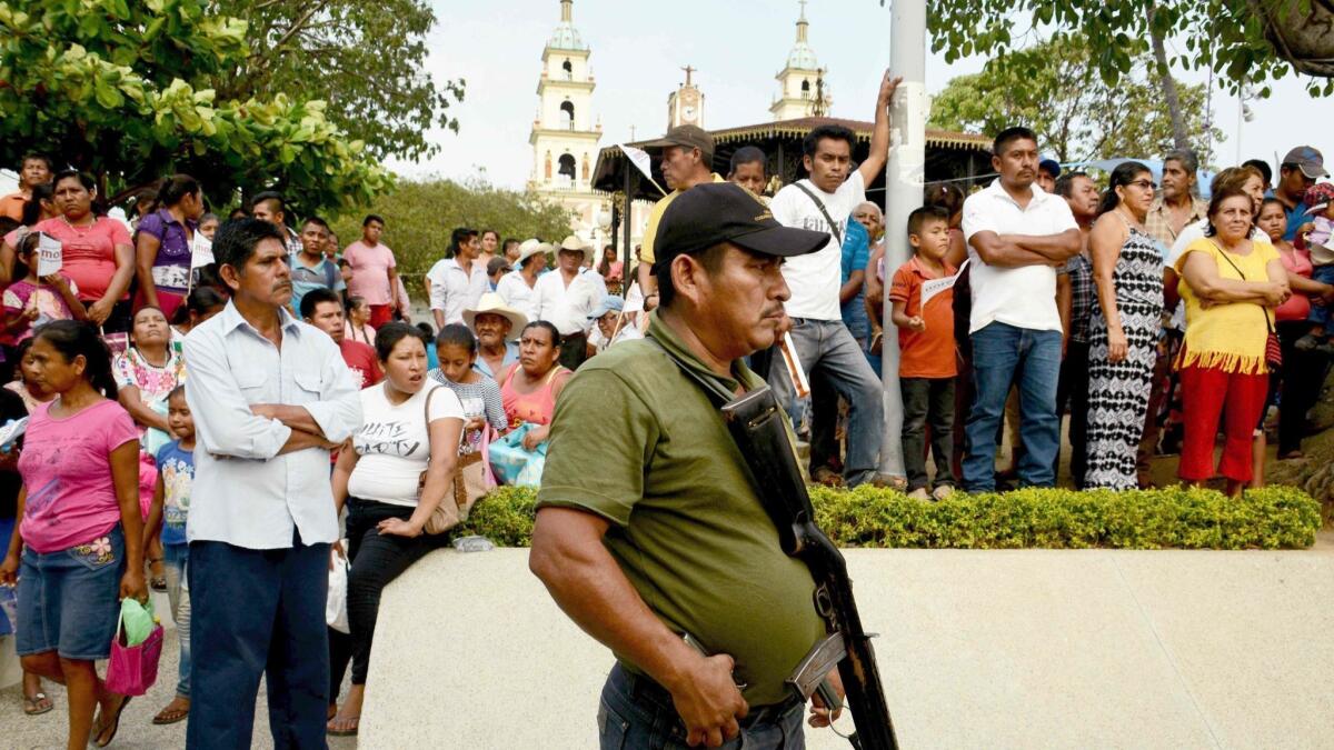 A security officer stands guard at a campaign appearance by a Senate candidate in San Luis Acatlan, Guerrero state.