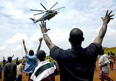 Liberians wave as U.S. Marine helicopters prepare to land Thursday at the port of Monrovia in support of West African peacekeepers. It is part of an effort to move humanitarian aid to the capital after the troops take control of the port from departing rebels.