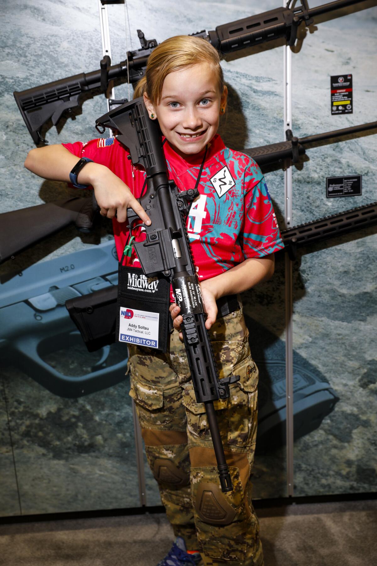 Addyson "Alpha Addy" Soltau, 9, poses with an M&P 15-22 Sport rifle, the gun she shoots with, while visiting the Smith & Wesson booth at the National Rifle Assn. meeting in Dallas.