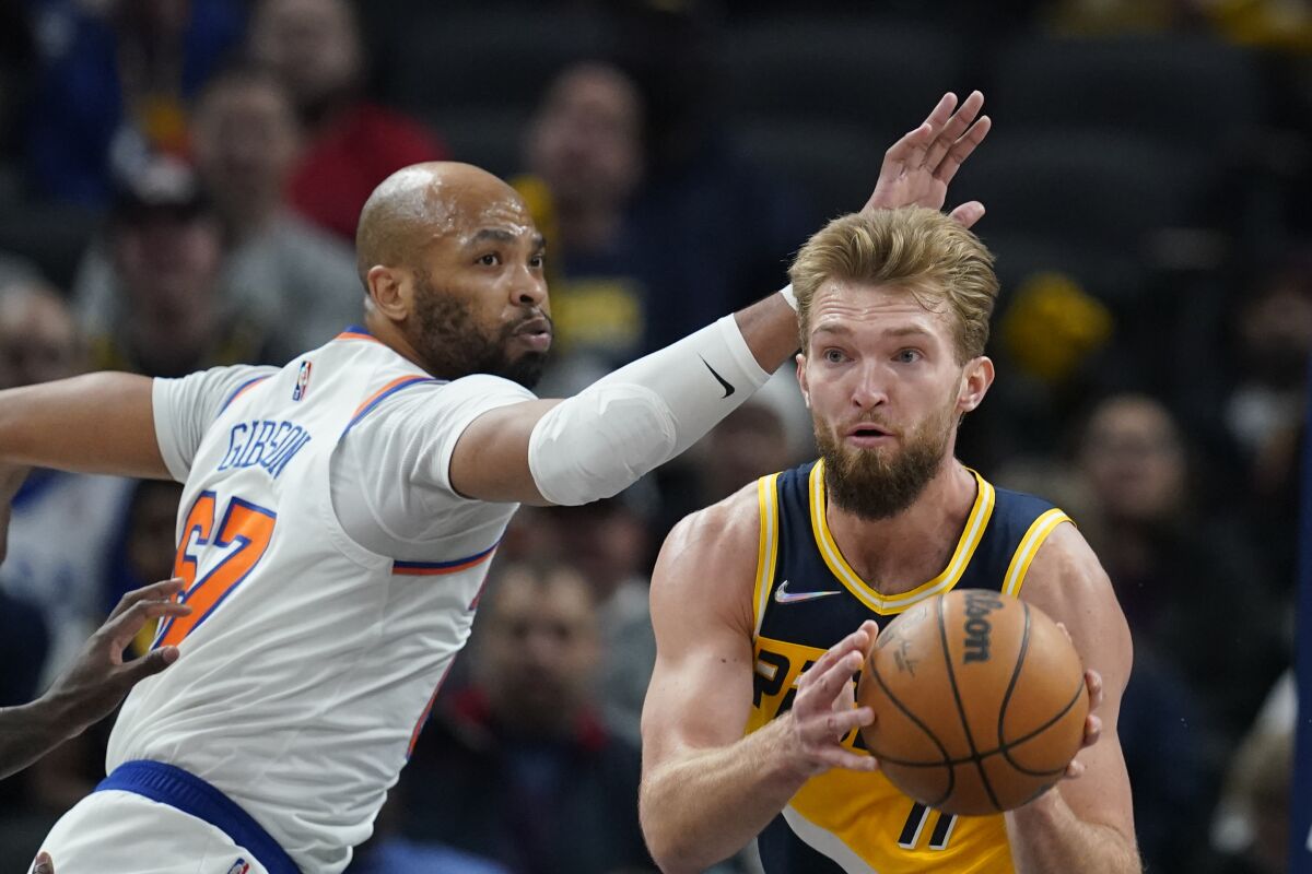 Indiana Pacers' Domantas Sabonis (11) passes the ball as New York Knicks' Taj Gibson (67) defends during the first half of an NBA basketball game Wednesday, Dec. 8, 2021, in Indianapolis. (AP Photo/Darron Cummings)